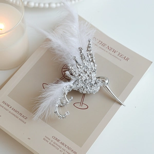 Elegant white feather hummingbird ornament with sparkling rhinestones on a vintage book decor