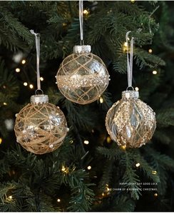 Close-up of clear 8cm Christmas ball with gold glitter lattice and pearl accents