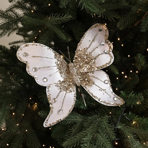 Sparkling white and gold Christmas butterfly bow clip on a decorated pine tree branch