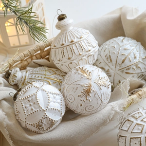 Vintage Weihnachtsanhänger in Weiß und Gold mit Schneeflockenmustern im rustikalen Korb