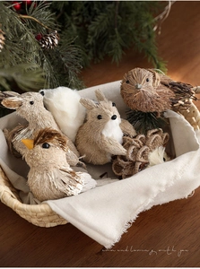 Detailansicht handgefertigter Stroh-Vögel und Hasen in einem gemütlichen Geschenkkorb