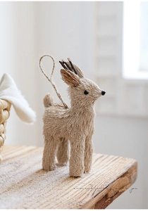 Detail von Rentier-Deko aus Stroh und Sisal mit Geweih auf verschneitem Holztisch