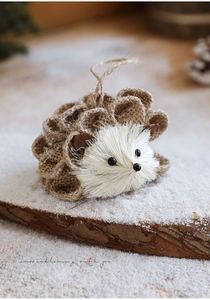 Nahaufnahme von Sisal-Igel-Anhänger mit Hanfseilschlaufe auf verschneitem Holzblock