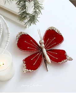 Detail of red velvet Christmas butterfly clip with gold glitter and pearls on pine branches