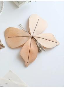 Close-up of elegant beige glitter butterfly ornament with metal clip on white background