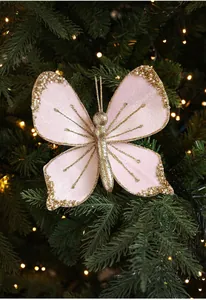 Pink velvet butterfly ornament with gold glitter on Christmas tree with warm lights