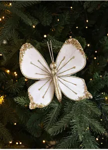 Detailed view of white velvet Christmas butterfly ornament with gold glitter on tree