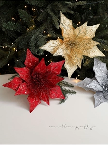 Close-up of sparkling poinsettia ornaments with glitter finish on a Christmas tree