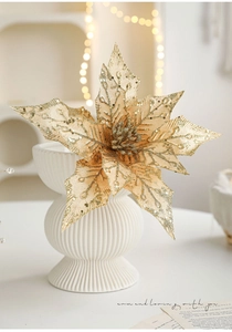 Detail of golden glitter poinsettia artificial flower in a white textured ceramic vase