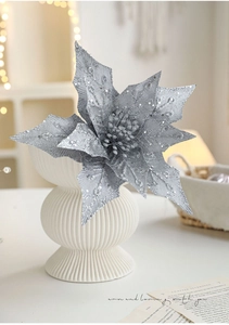 Macro shot of silver sequined artificial poinsettia flower in a white textured vase
