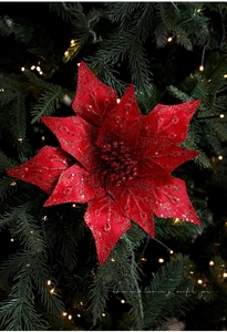Close-up of red glitter poinsettia flower on a decorated Christmas tree with lights