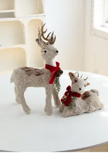 Detail of reindeer figurines made of straw and jute with red bows for Christmas decor
