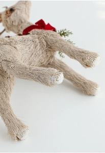 Detail of straw woven Christmas elk with red velvet bow and golden glitter accents