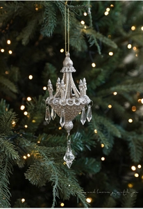 Macro detail of silver glitter chandelier ornament with clear teardrop crystals on a tree