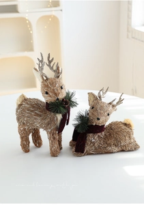 Detail of sisal elk figurines with red scarves and pine needles for Christmas decor