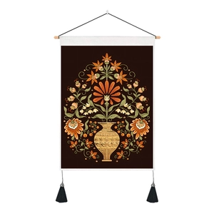 Detalle de tapiz floral con varilla de madera clara y borlas decorativas negras
