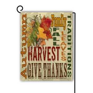 Close-up detail of autumn garden flag featuring maple leaves and acorns on a metal stand