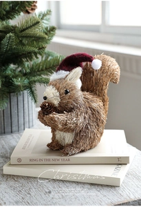 Detail of Christmas straw squirrel figurine holding a pine cone on a cozy desktop