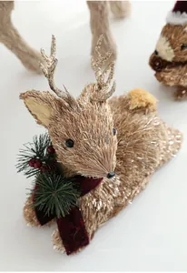 Detail of a straw reindeer figurine with silver glitter and a red scarf decoration