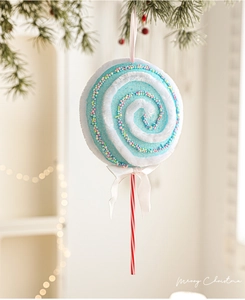 Détail d'un ornement sucette de Noël bleue avec paillettes et ruban sur branche de pin