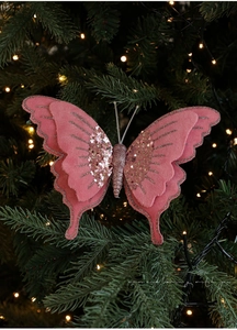 Dettaglio di farfalla in velluto rosa con glitter su un albero di Natale verde