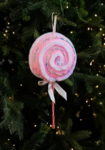 Détail d'un ornement sucette rose pailletée avec bordure en peluche sur un sapin