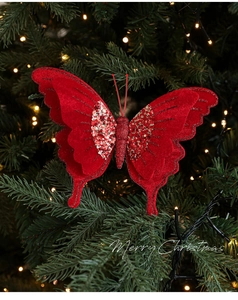Dettaglio di farfalla natalizia in velluto rosso con paillettes su albero verde