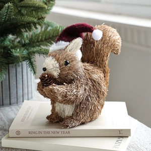 Handcrafted straw squirrel figurine with red Christmas hat and pine cone on books
