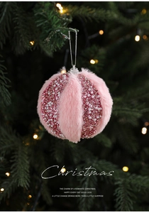 Pink plush Christmas ball ornament with sparkling beads hanging on a festive tree branch