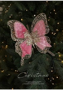 Détail d'un papillon de Noël en velours rose avec paillettes dorées sur sapin