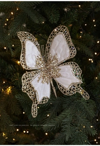 Détail d'un nœud papillon en velours crème avec paillettes dorées sur un sapin de Noël