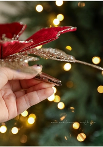 Détail de fleur de Noël en velours rouge avec feuille pailletée dorée et clip métal