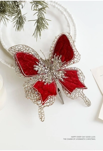 Détail d'un papillon de Noël en velours rouge avec paillettes dorées et perles