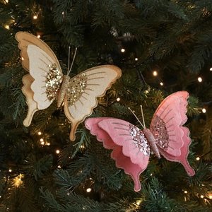 Farfalla natalizia in velluto rosa e champagne con paillettes su rami verdi dell'albero