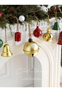 Detail of metal Christmas bells with rustic twine hanging on a festive mantelpiece