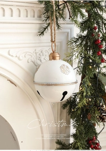 Macro detail of creamy white Christmas bell with gold snowflakes on white fireplace