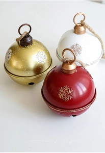 Detailed close-up of metal Christmas bells with snowflake relief and jute ropes