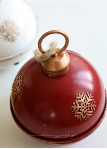 Close-up of red metal Christmas bell with golden snowflakes and rustic jute rope