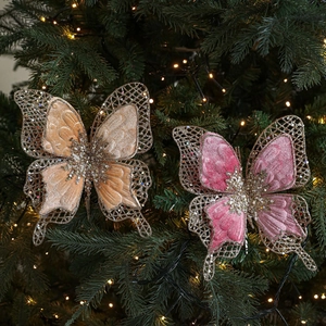 Ornements papillon en velours rose et champagne avec paillettes sur un sapin de Noël