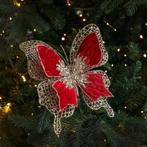 Papillon de Noël en velours rouge avec ailes dorées sur un sapin décoré de lumières