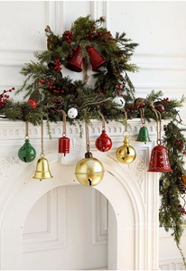 Detail of metal Christmas bells with star cutouts hanging from rustic jute ropes