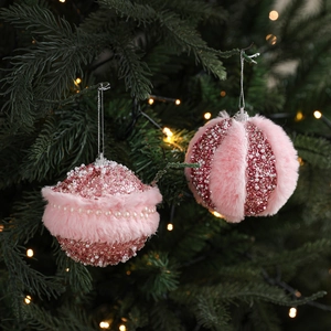 Pink plush Christmas ball ornaments with pearls hanging on a festive tree with warm lights