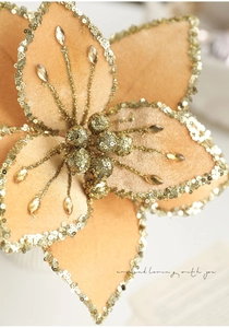Macro detail of 26cm golden fabric Christmas flower with glitter edges and faux gems