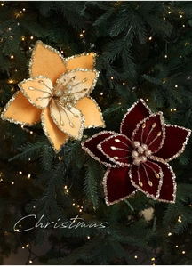 Close-up of velvet poinsettias with gold sequins on a Christmas tree with warm lights