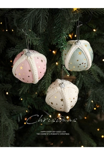 Detail of fabric Christmas balls with gold stars hanging on a festive tree branch