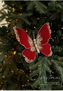 Detail of red velvet Christmas butterfly ornament with gold sequins on a festive tree