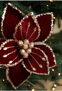 Macro detail of wine red velvet Christmas flower with gold sequins and beaded stamens