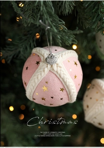 Detail of pink fabric Christmas ball with gold stars and knit ribbon on tree