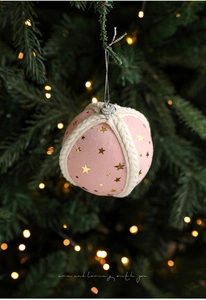 Pink matte Christmas ball with gold stars and white knitted mesh on tree branch