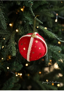 Detail of red Christmas foam ball with gold stars and rustic rope on festive tree